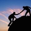 Persona che aiuta un'altra persona a scalare una roccia